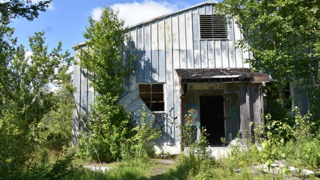 The mess hall sits to crumble with trash, graffiti, and overgrown plants.